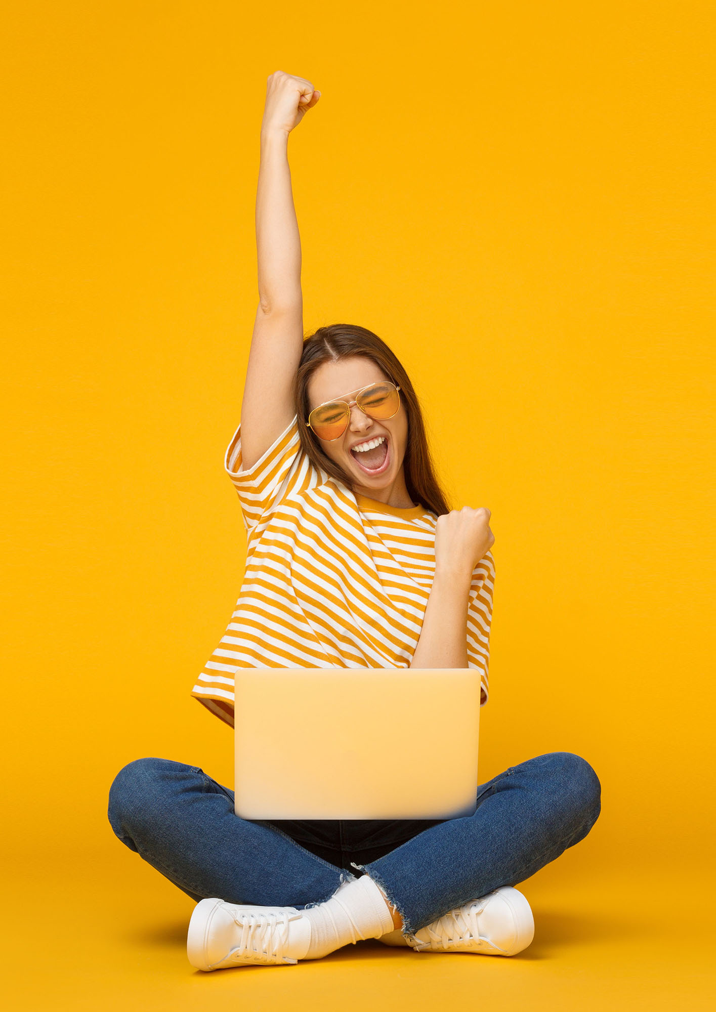 She is a winner! Excited young female with laptop isolated on yellow background