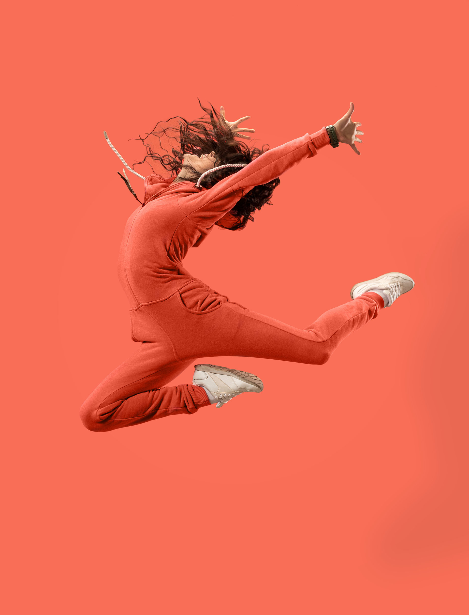 Freedom in moving. Pretty young woman jumping against coral background